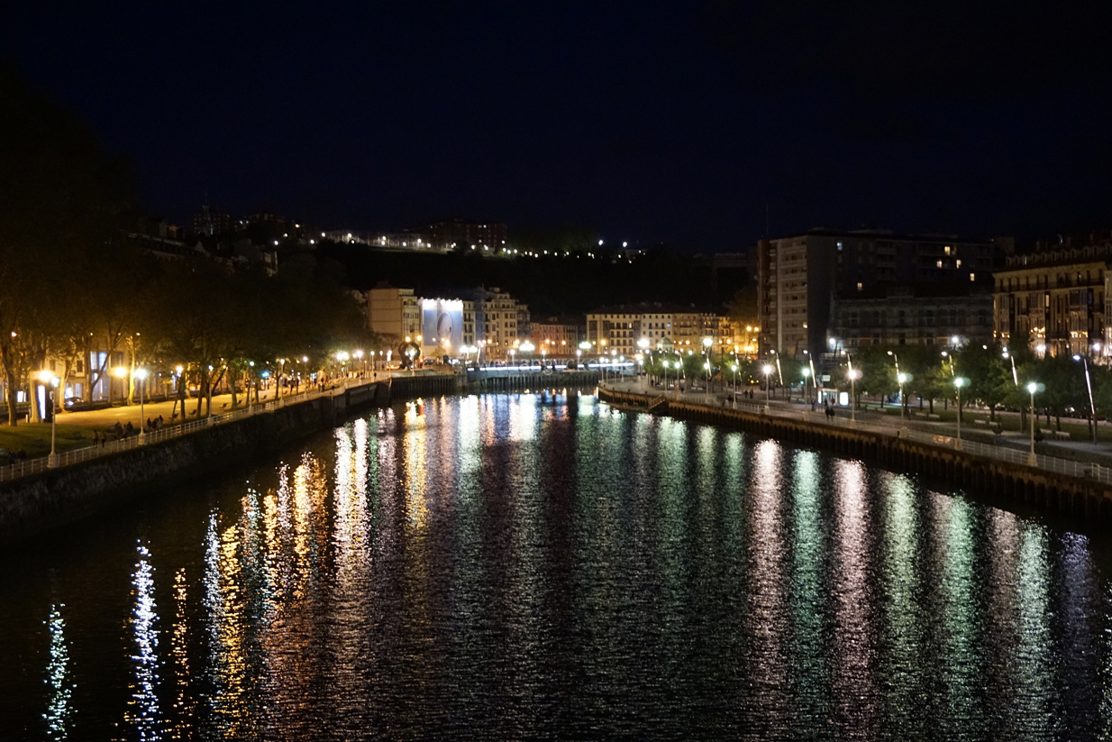 Blick von der Fußgängerbrücke Zubizuri in Bilbao bei Nacht (Baskenland, Spanien)